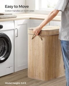 Person carrying a bamboo laundry basket beside a washing machine